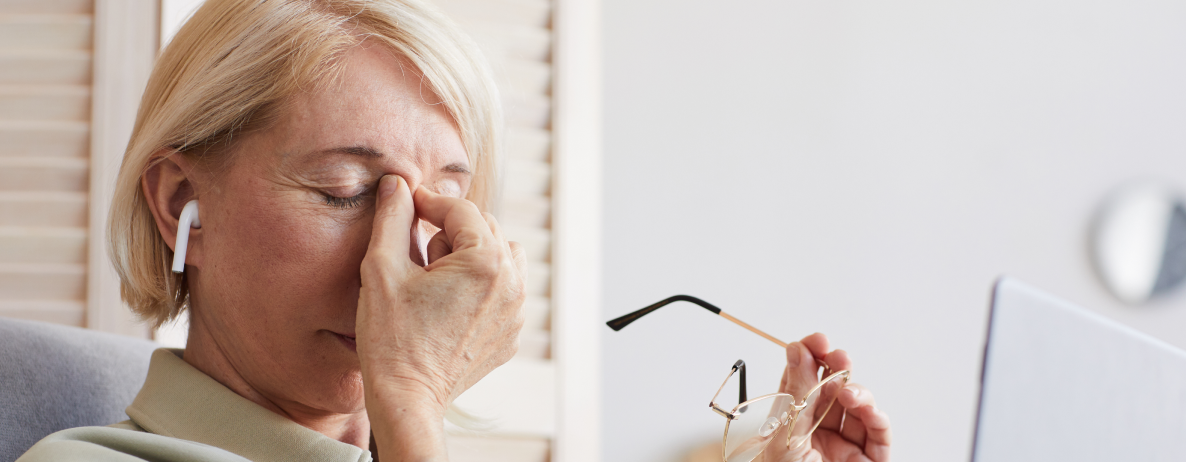 Elderly woman feeling eye discomfort holding glasses